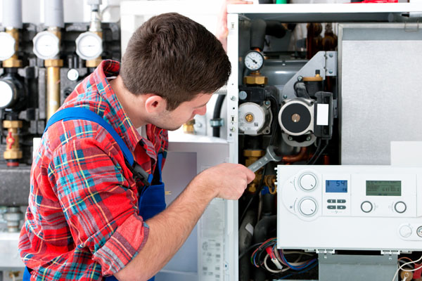 HVAC technician inspecting and repairing boiler controls in Denver