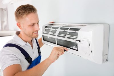 HVAC technician cleaning and repairing a ductless mini split AC in Denver, CO