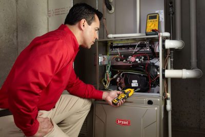 Heating and air conditioning technician servicing an indoor furnace in Denver, CO